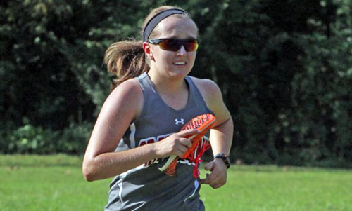 Gray Stone's Sara Bruinsma fights through the pain of the last few meters of Tuesday's cross-country meet holding her left shoe in her hand